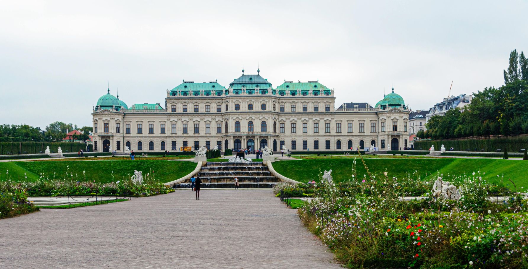 Das Schloss Belvedere in Wien mit seinen pr&auml;chtigen G&auml;rten und Springbrunnen, umgeben von bl&uuml;henden Blumen im Fr&uuml;hling.